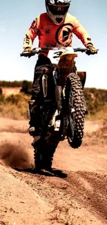 Dirt biker performs wheelie in desert.