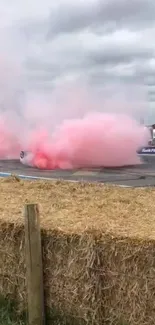 Car drifting with pink smoke on track.