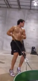 Shirtless athlete in gym with equipment performing workout.