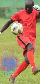 Goalkeeper in red kicking soccer ball on green field.