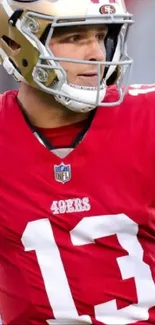 Football player in striking red uniform with gold helmet on the field.