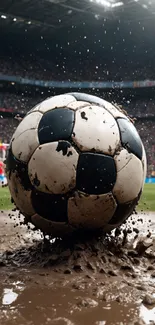 Muddy soccer ball splashing on field with stadium background.