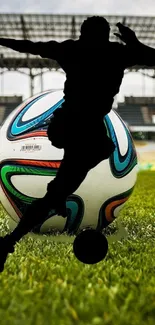 Silhouetted player with football on green field in a stadium background.