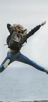 Traveler jumps energetically by the ocean with a dynamic blue background.