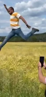 Man leaping energetically in a sunny field, captured on a mobile phone.