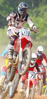 Motocross riders in action on a dirt track amid dust.