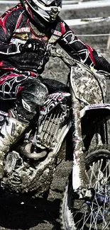 Motocross rider on dirt bike in action, covered in mud against a gritty backdrop.