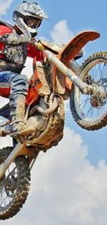 Motocross rider performing aerial stunt on a dirt bike with blue sky background.