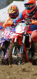 Two motocross riders racing fiercely in colorful gear on a dirt track.