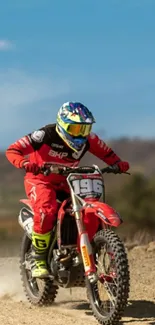 Motocross racer in vibrant red gear, speeding across a dirt track.