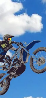 Motocross biker jumps high against a vivid blue sky.