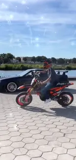 Motorcyclist rides near car by riverside, clear sky above.