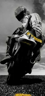 Motorcycle racer riding on asphalt with cloudy sky backdrop.