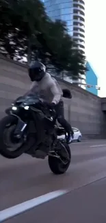 Motorcyclist performing a wheelie on a city street at dusk.