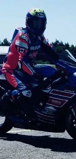 Rider on red and blue motorcycle at racing track.