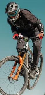 Mountain biker mid-jump against sky blue background.