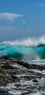 Vibrant ocean waves crashing on rocks under a blue sky.