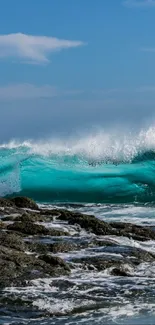 Dynamic ocean wave crashing over rocks with a blue sky background.