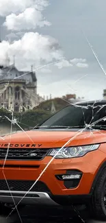 Orange SUV with cracked glass effect and urban backdrop.