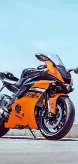 Vibrant orange motorcycle on open road, sleek design.