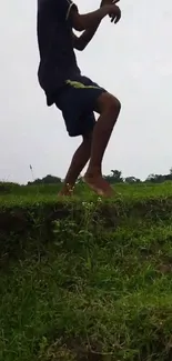 Person jumping on green grass in a scenic outdoor setting.