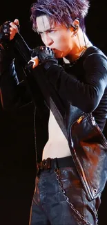 Dynamic performer on stage in black leather attire, holding a microphone.