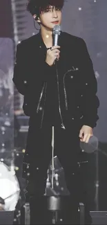 Performer in black outfit holding microphone on stage.