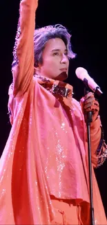 Performer in vibrant red outfit holds microphone on stage.