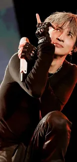 Charismatic performer posing on stage with black attire and gloves.