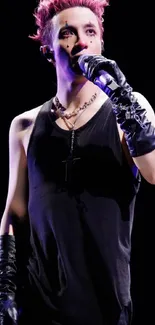 Performer in black outfit on colorful stage with microphone.