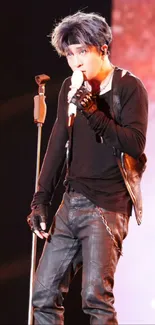 Performer on stage in black outfit with microphone.