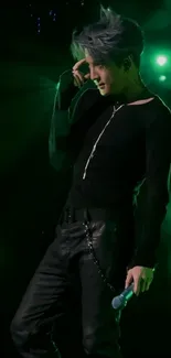 Energetic performer on stage with green lighting and black outfit.