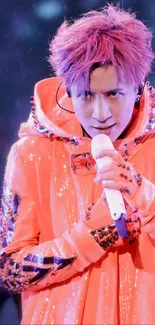 Energetic performer in orange coat holding microphone on stage.