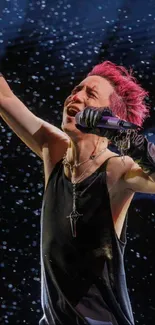 Performer with pink hair in dynamic pose on dark backdrop.