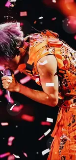 Performer in orange attire with confetti shower on stage.