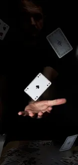 Floating playing cards in dramatic black background, hand in motion.