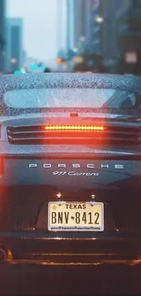 Porsche 911 Carrera on rainy city street, rear view wallpaper.