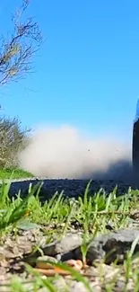 Dynamic racing scene with car on gravel road and clear blue sky.