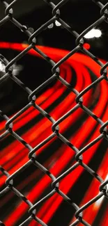 Red light trails through a metal fence at night.