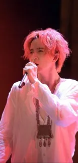 Dynamic singer performing on stage with vibrant red-orange lighting.