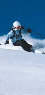 Skier descending snowy mountain under a blue sky.