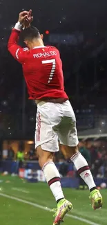 Soccer player jumps celebrating a goal at night stadium.