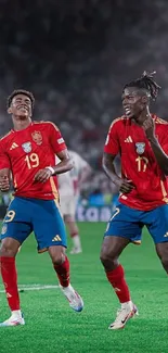 Two soccer players celebrating on field in vibrant red and blue uniforms.