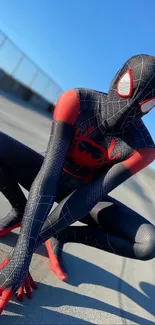 Spider-themed hero crouching under a clear blue sky in vibrant suit.