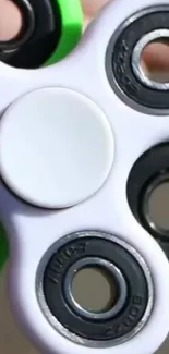 Close-up of a green and white fidget spinner on wallpaper.