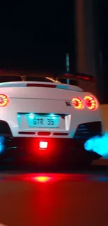 White sports car with blue flame exhaust at night.