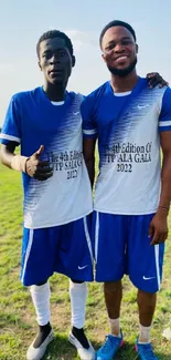 Dynamic duo in blue sports jerseys on a sunny field.