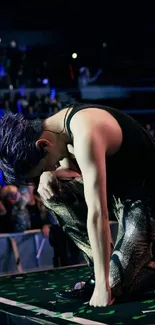 Dynamic performer kneels under stage lights.