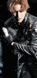 Stage performer in black and silver glittery suit holding microphone.