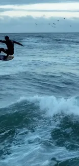 Surfer jumping over ocean waves under a blue sky.